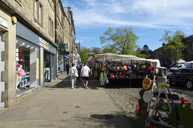 Shoppers walking past colourful stalls at Skipton Market on the High Street