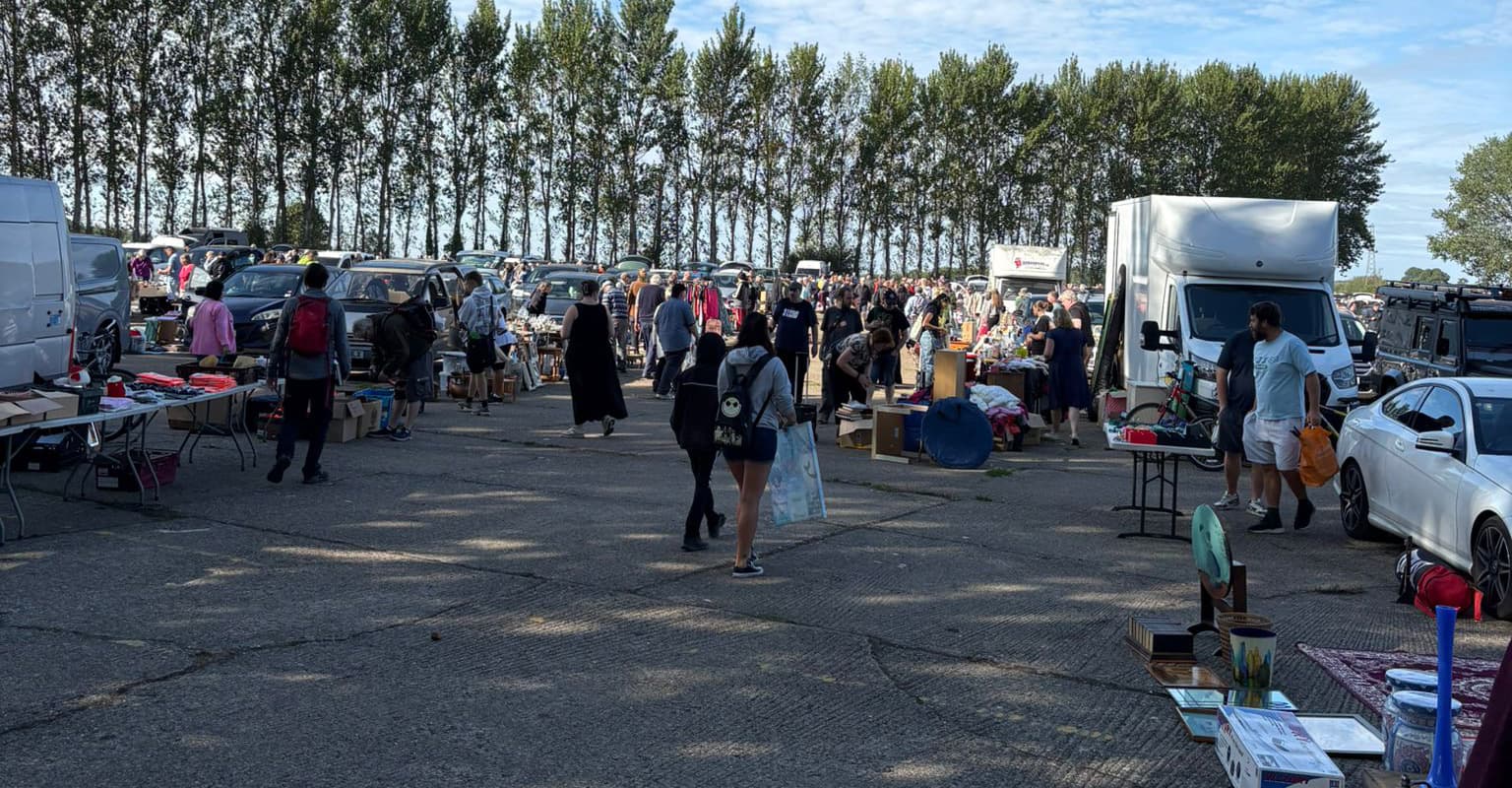 Busy central aisle at Finmere Car Boot Sale with cars, vans, stalls and shoppers. Source: https://www.finmerecarbootsale.co.uk/wp-content/uploads/2025/08/Finmere-9.jpg