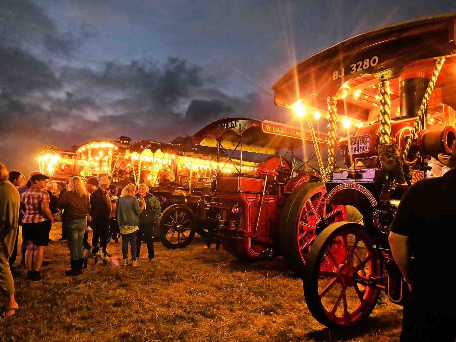 Visitors walking among illuminated steam engines at Torbay Steam Fair. Source: https://torbaysteamfair.co.uk/gallery/