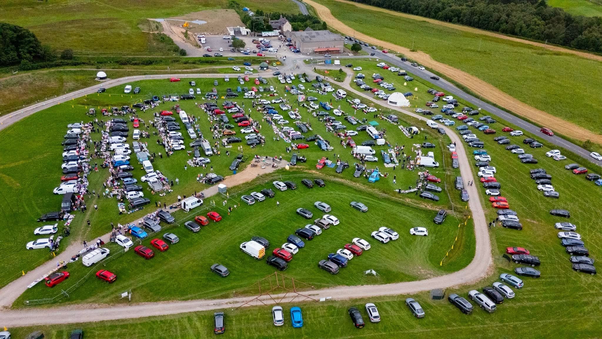 Drone view of rows of seller vehicles, goods and shoppers at Aberdeenshire Car Boot. Source: https://www.facebook.com/photo.php?fbid=1323320249928648&set=pb.100067520573427.-2207520000&type=3