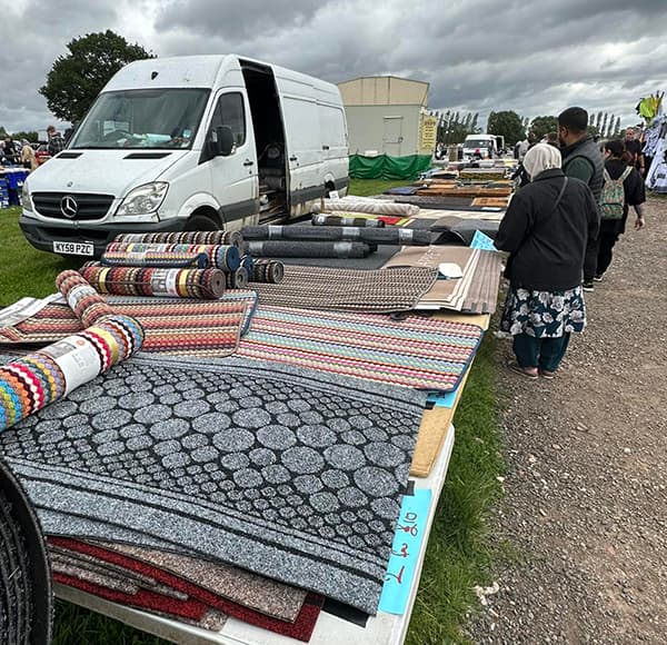 Shoppers browsing rugs beside a seller van at Furnace End Market and Car Boot. Source: https://furnaceendcarboot.co.uk/wp-content/uploads/2023/11/405775132_658947839699033_8077903579465941180_n.jpg