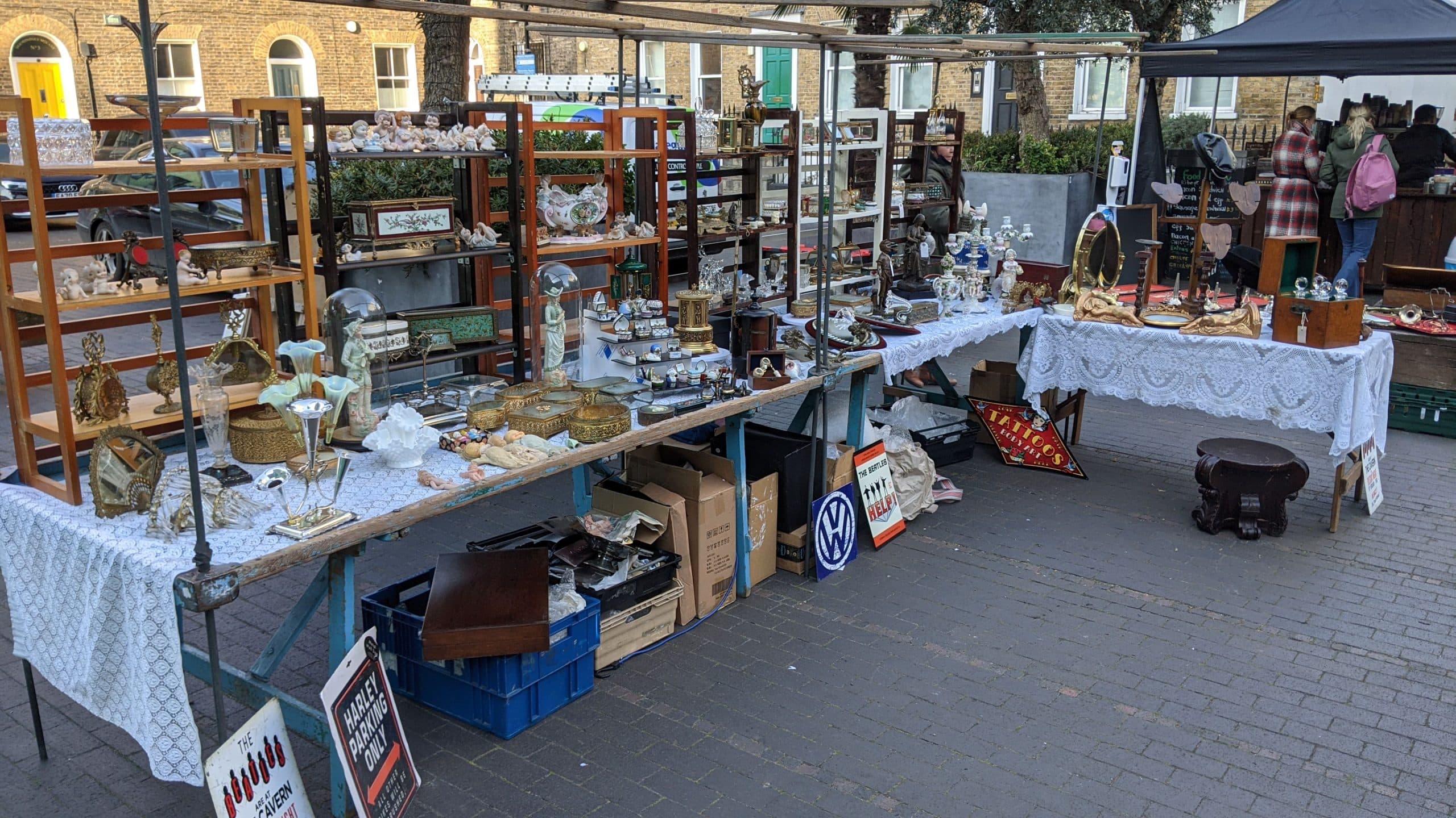Outdoor Bermondsey Antique Market stalls with antiques, collectables and shoppers at Bermondsey Square. Source: https://bermondseyantiquemarket.co.uk/wp-content/uploads/2023/01/BAM14-1-scaled.jpg