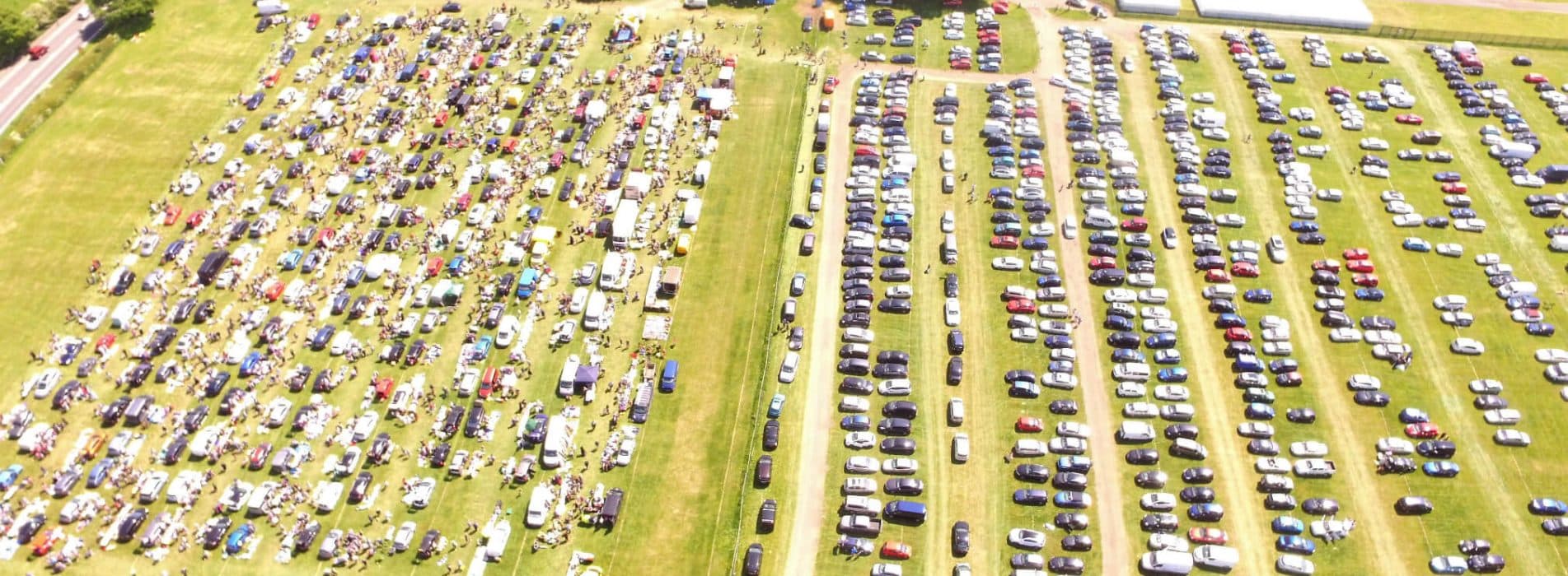 Aerial view of Redbourn Car Boot Sale with cars, sellers and shoppers at the Herts Showground. Source: https://www.countrysidepromotions.co.uk/wp-content/uploads/2022/01/Redbourn-car-boot-sale-20th-May-2018-1903x700.jpg