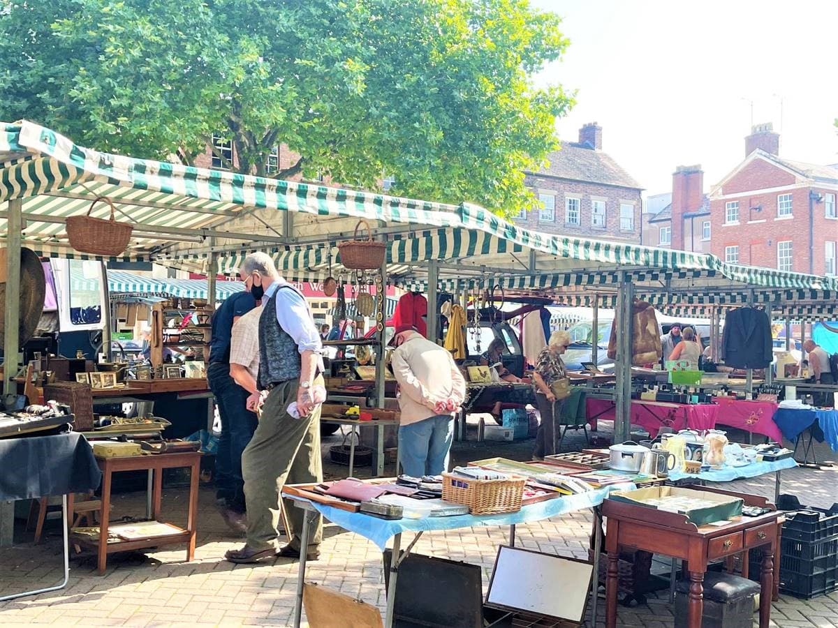 People browsing antiques and collectibles stalls at Newcastle-under-Lyme market. Source: https://www.newcastle-staffs.gov.uk/images/Antiques_market.jpg