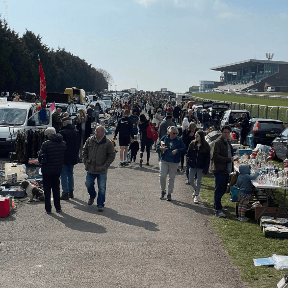 Busy Brighton Racecourse car boot with the grandstand, cars, goods and shoppers Source: https://brightoncarbootsale.co.uk/wp-content/uploads/2023/01/image1153-1.png