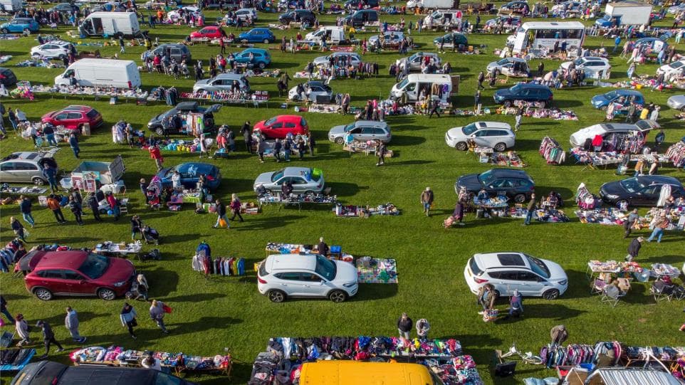 Cars with open boots and visitors browsing the grass field at Skylark Car Boot Source: https://www.wisbechstandard.co.uk/news/22645934.hundreds-go-bargain-hunting-sun-first-car-boot-since-lockdown/