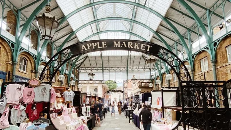 Craft stalls and shoppers beneath the Apple Market sign at Covent Garden. Source: https://www.coventgarden.london/shop/markets