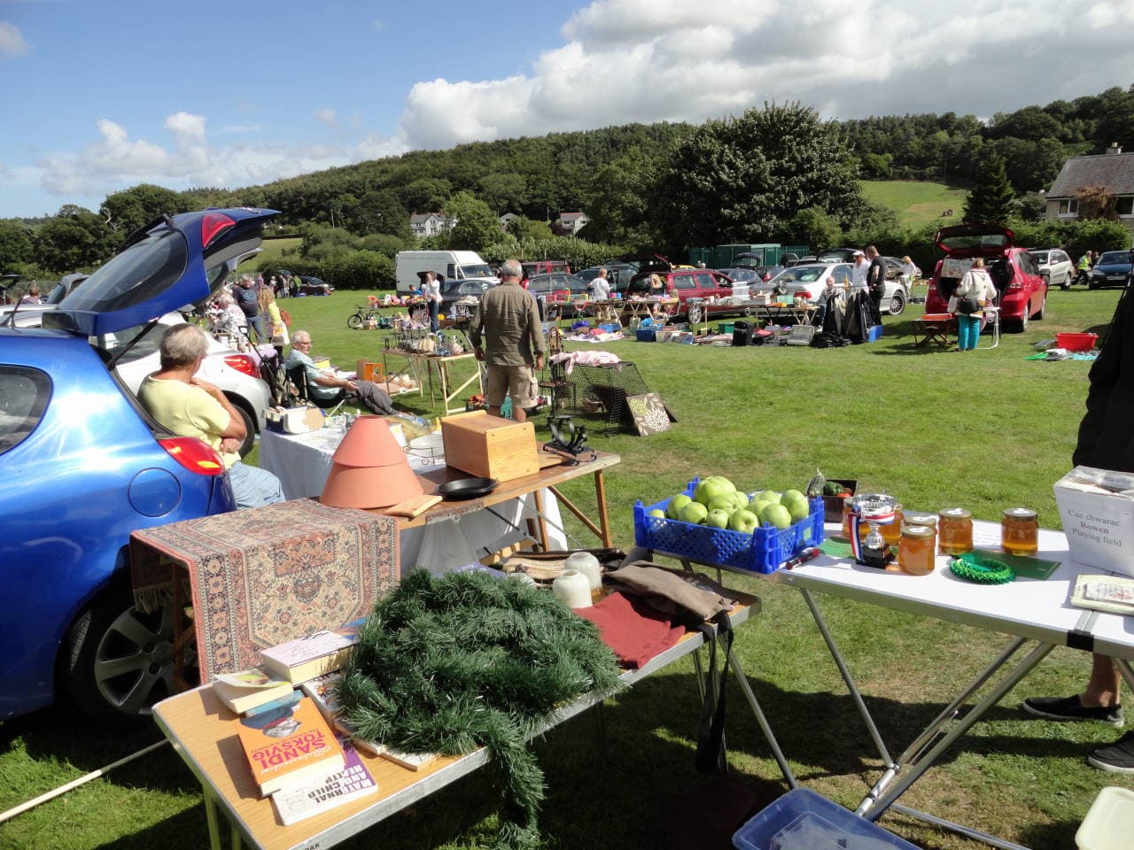 Seller tables, open cars and visitors on Rowen Playing Field Source: https://rowenconwy.org.uk/community-group/car-boot-sales/rowen-car-boot-sales-1/