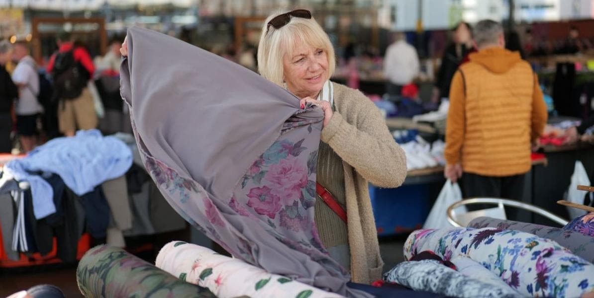 A shopper browsing fabric stalls under Preston Outdoor Market's Victorian canopy. Source: https://www.prestonmarkets.co.uk/Welcome-to-Preston-Outdoor-Market
